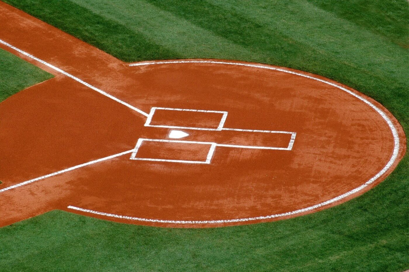 Aerial view of a baseball field's home plate area, featuring the pitcher's mound, batter's boxes, and foul lines on a well-maintained Sports Field Artificial Turf.